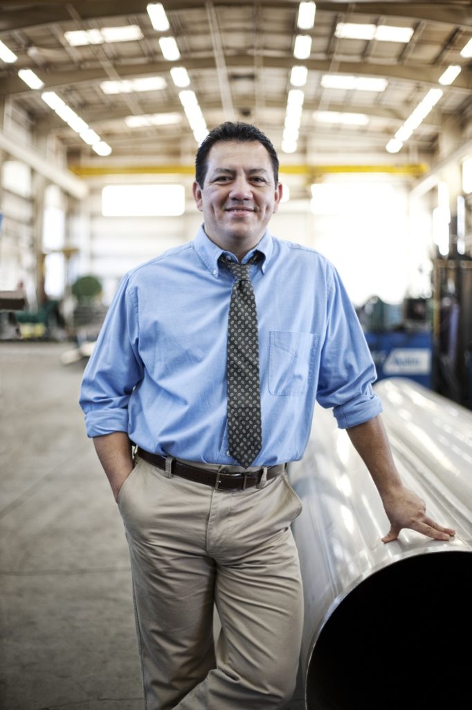 Hispanic man manager in a large sheet metal factory.